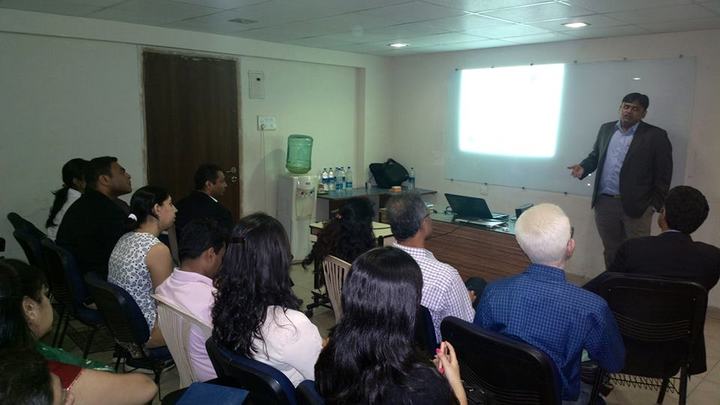 Rohit Shah presenting to a seated audience in an office.