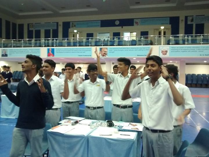 Students in a classroom raising their hands enthusiastically.