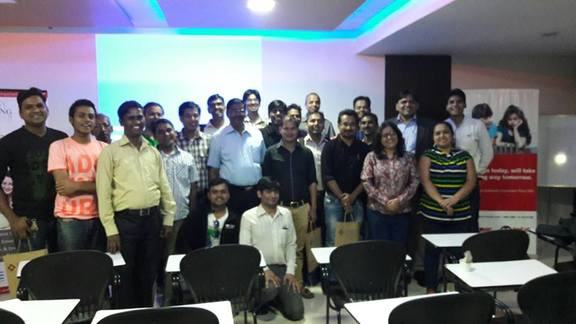 A large group of participants stands together in a training room.