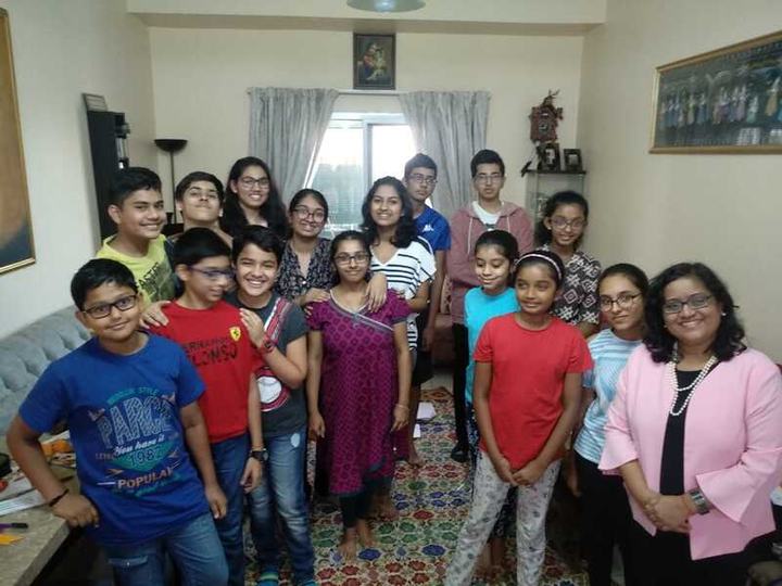 A large group of children and a few adults in a living room.