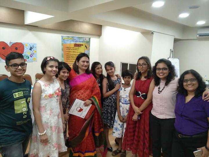 Children and parents stand together in a room decorated with colourful posters.