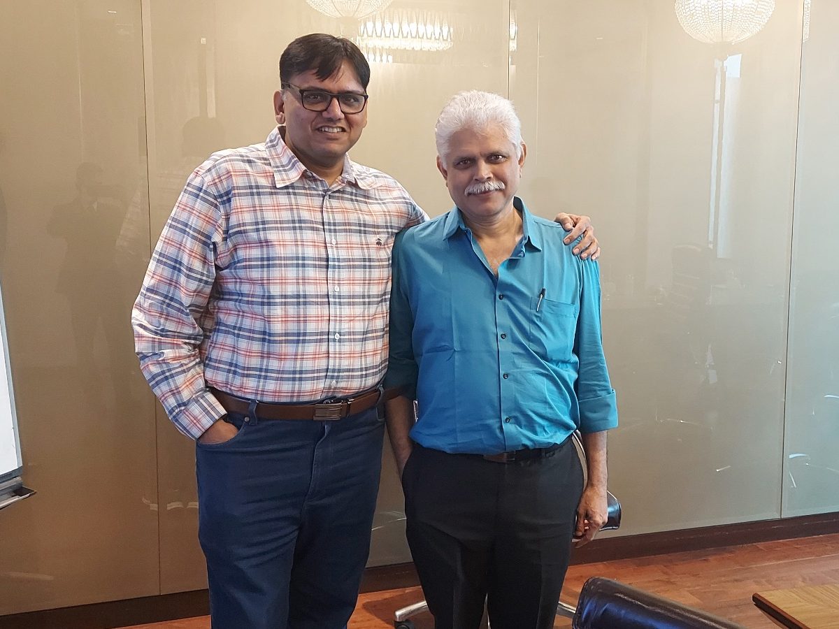 Rohit Shah and Yogin M. Sabnis standing together in a meeting room, Rohit's arm around Yogin's shoulder.